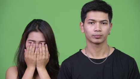 young upset asian man with young asian woman covering face