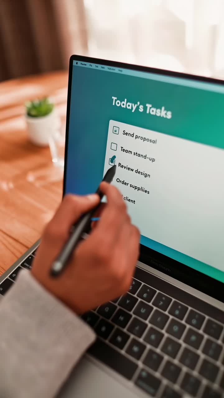 Close-up angle of a hand pointing at a laptop screen displaying a task list, ideal for video