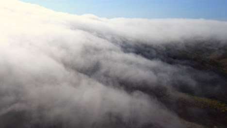 looking from above the low-lying fog in brisbane, california - aerial view of a misty morning