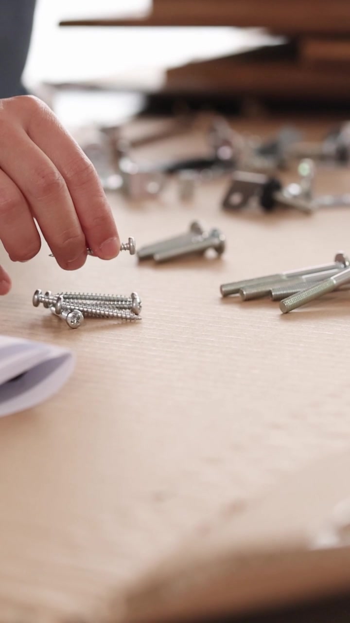 Close-up shots of hands organizing various screws, bolts, and metal hardware for furniture assembly.
