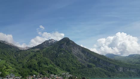 Majestic-Swiss-Alps-with-carpet-of-green-forests-and-peaceful-town,aerial