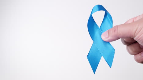 detail of male hand holding ribbon in light blue color on white background