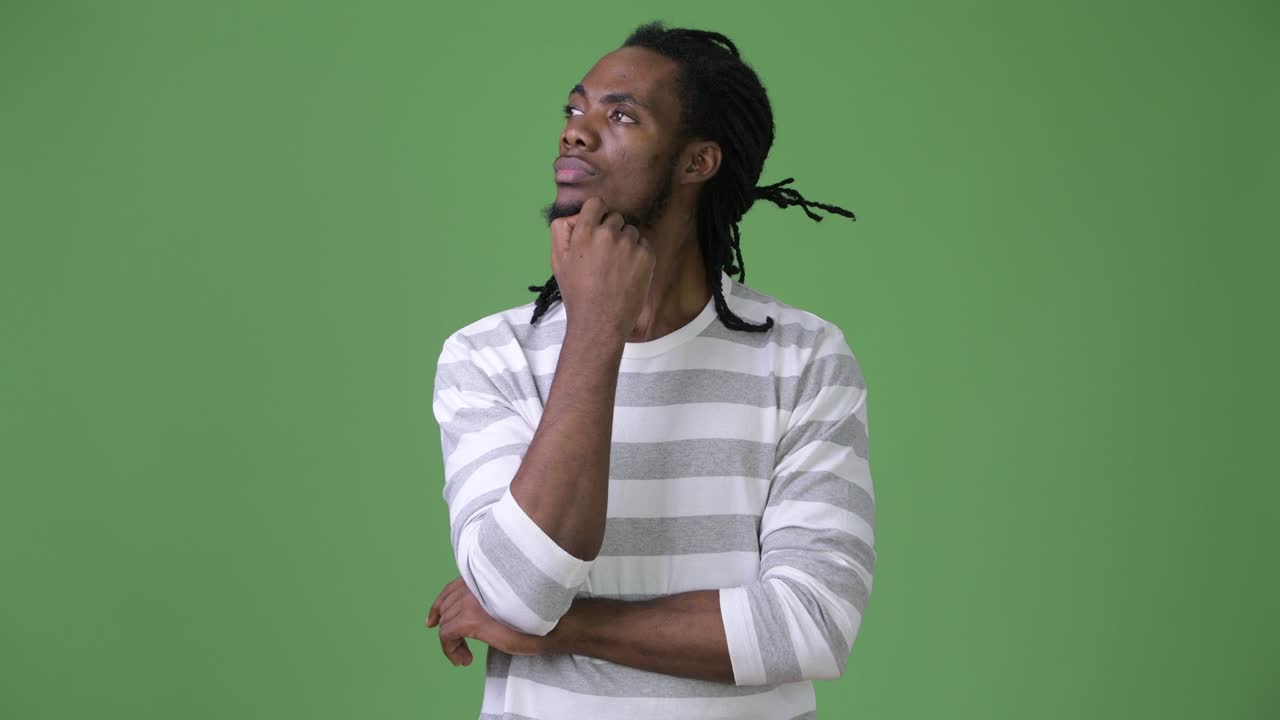 Young handsome African man with dreadlocks against green background