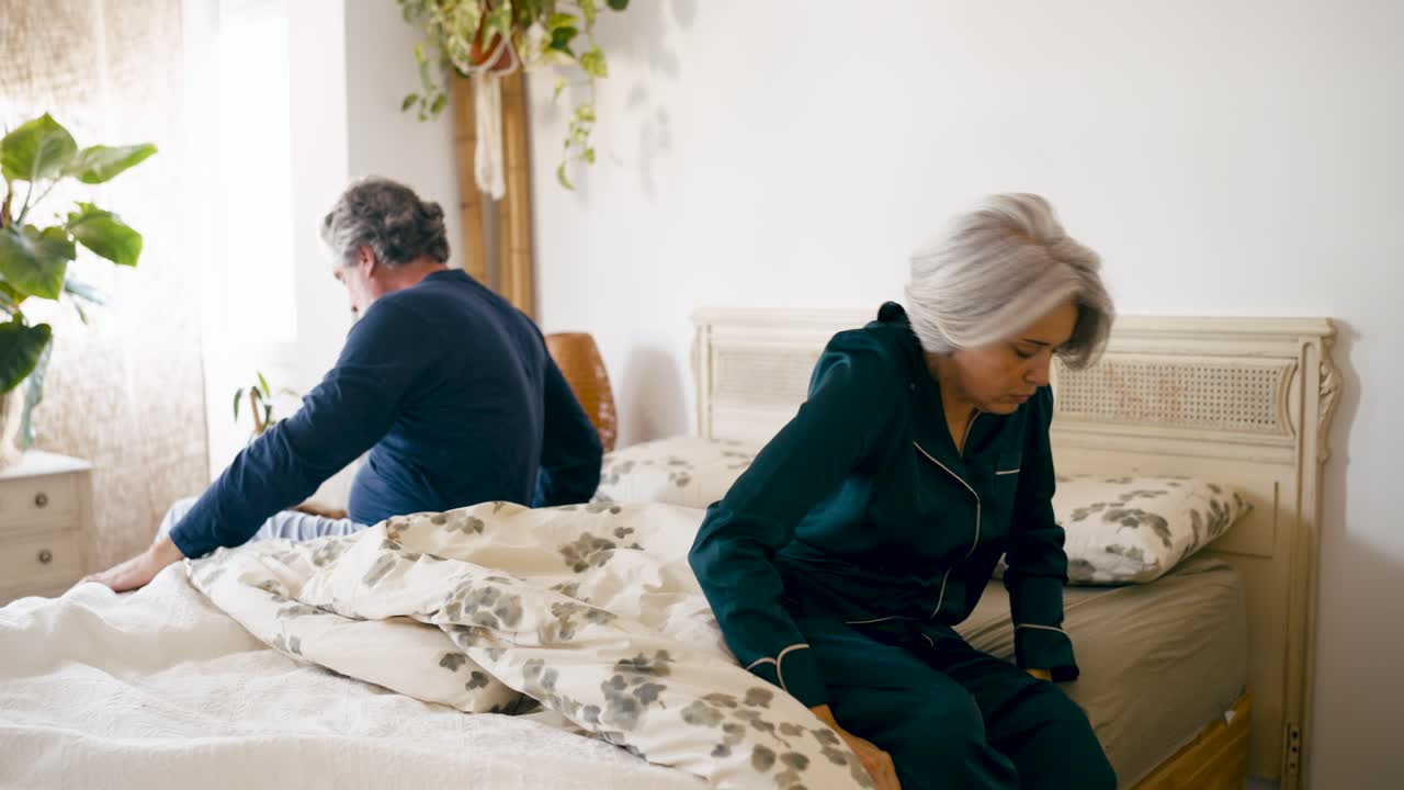 Casal maduro acordando com dor nas costas em um quarto iluminado