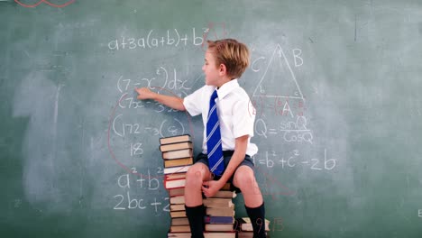 Animation-of-geometrical-shapes-over-caucasian-boy-writing-on-blackboard