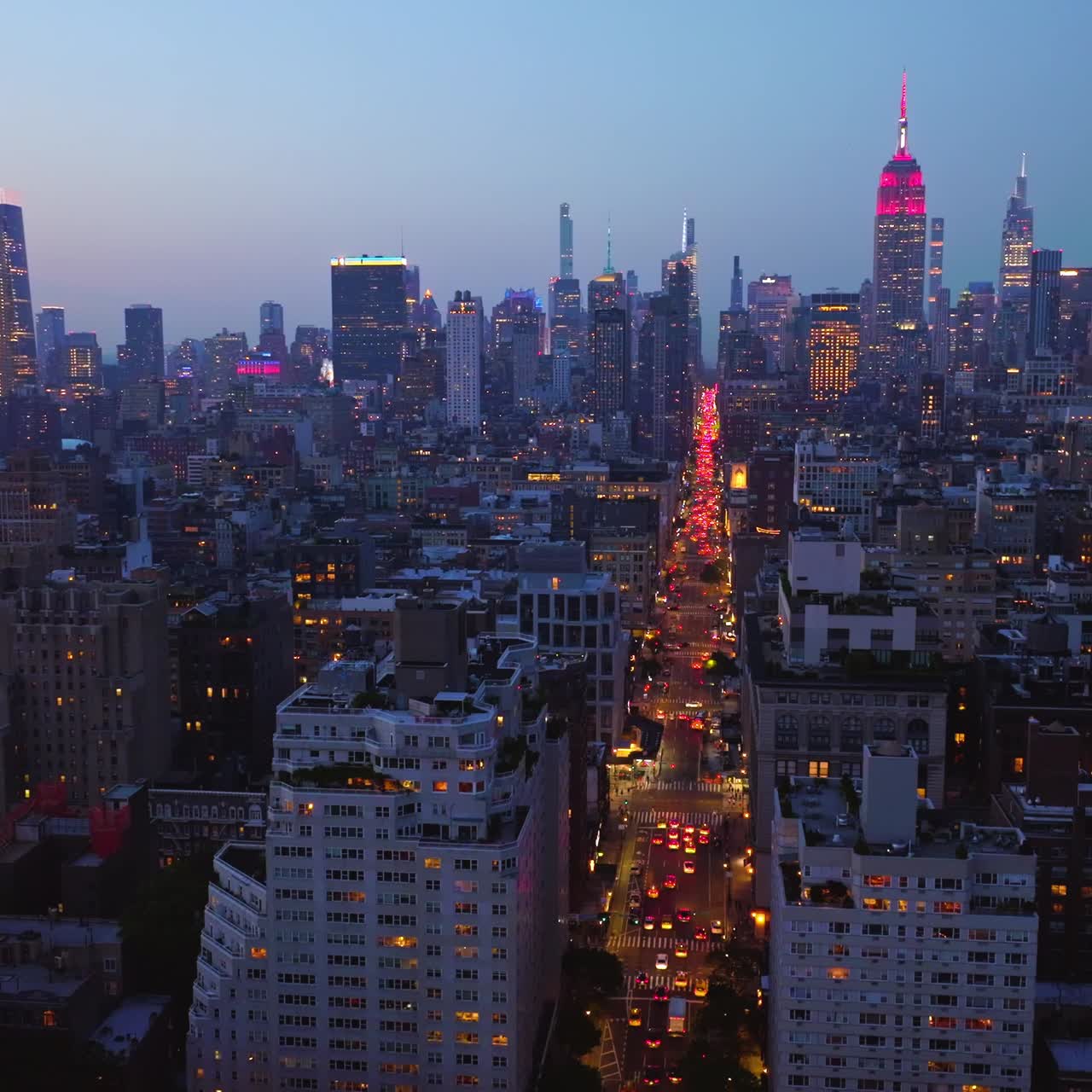 Sparkling tops of glamorous skyscrapers of New York at dusk time. Well-lit highway with multiple cars. Splendid city panorama in the coming night from top