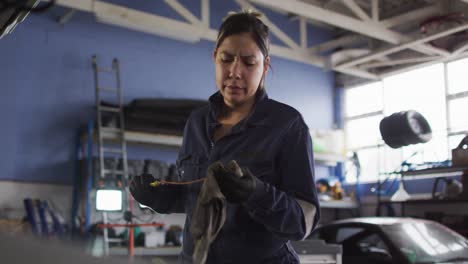 Female-mechanic-cleaning-equipment-of-the-car-with-a-cloth-at-a-car-service-station