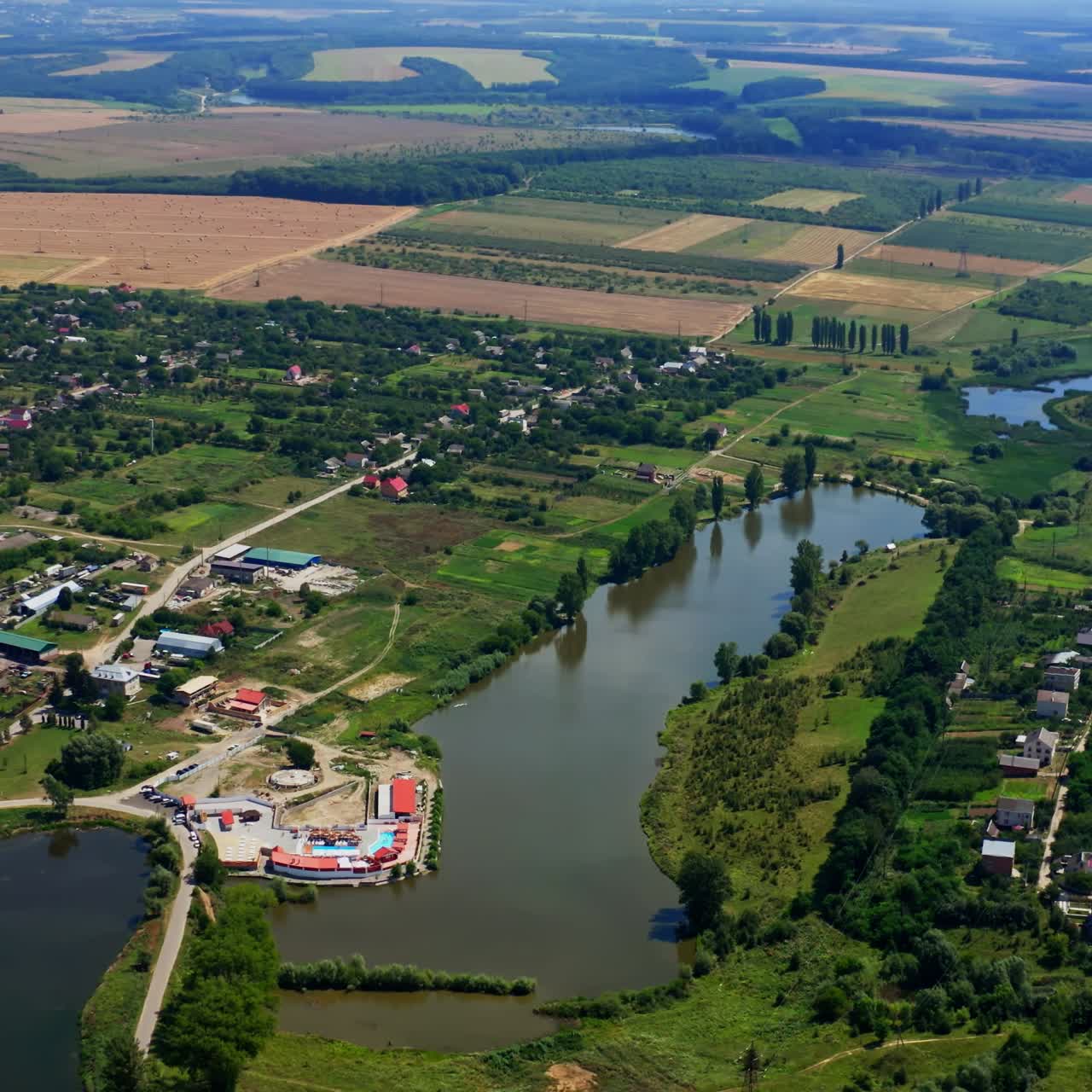 Panoramic landscape in summer. Nature scenery in the countryside. Agricultural fields, lakes and small houses in summer. Aerial view.