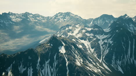 Aerial-Over-Valley-With-Snow-Capped-Mountains-In-Distance