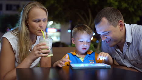 Niño-Usando-Tablet-Pc-Sentado-En-La-Cafetería-Con-Sus-Padres