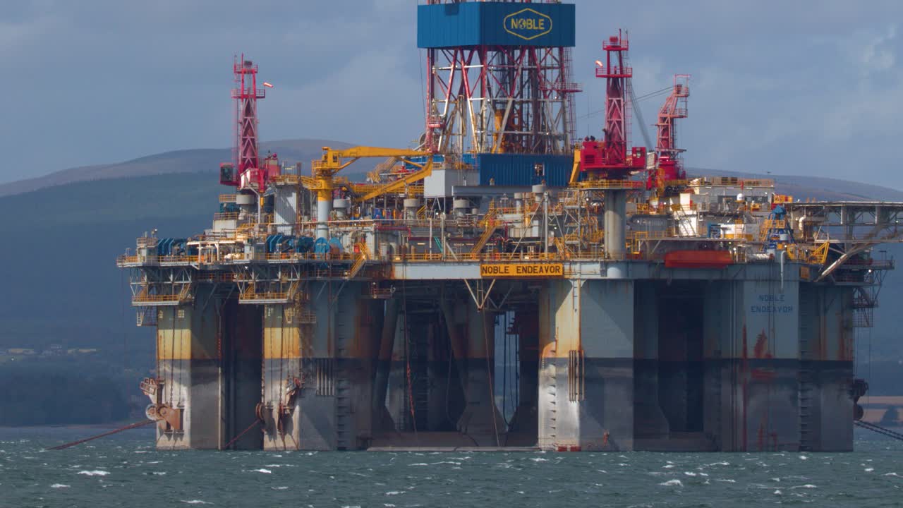 Stor offshore boreplatform bevæger sig mod kysten, dagslys, stabilt kamera, fjerne bakker, maritimt miljø