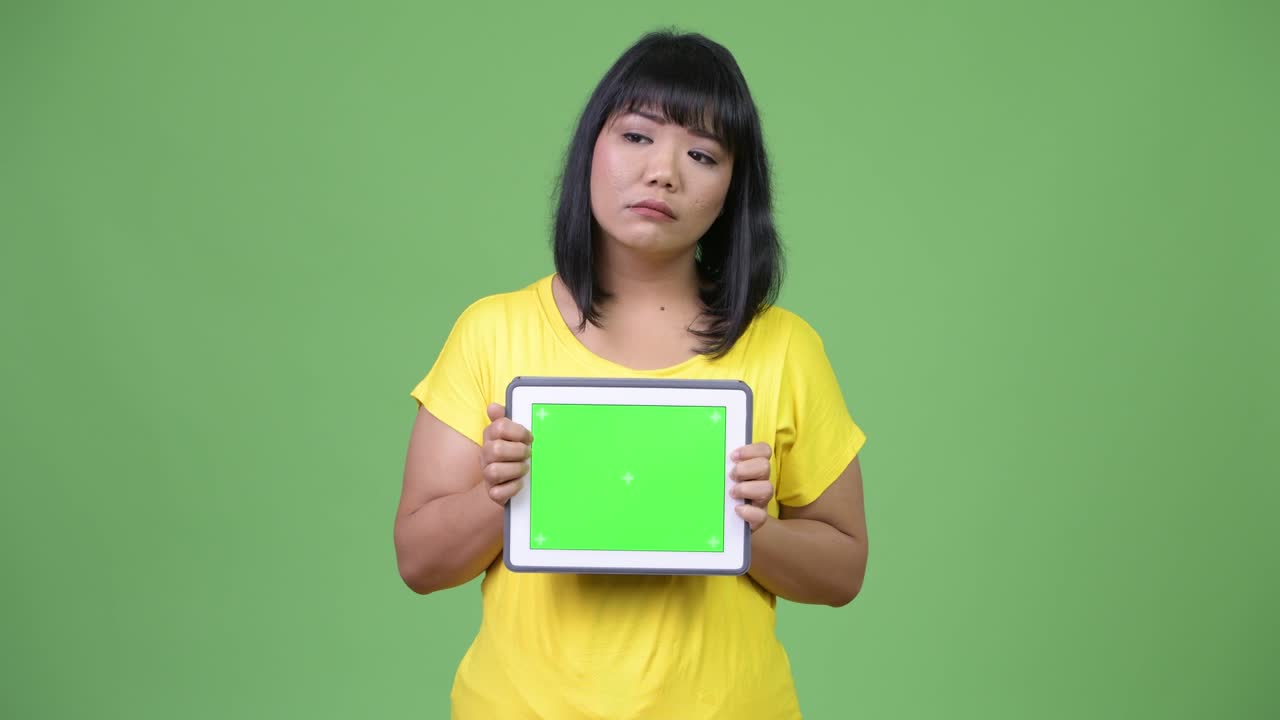 Beautiful Asian woman thinking while showing digital tablet