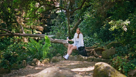romantic girl sitting tree trunk lying forest. woman relaxing after nature walk.