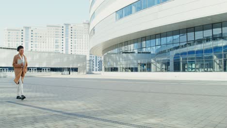 mujer de negocios caminando frente a un edificio de oficinas moderno