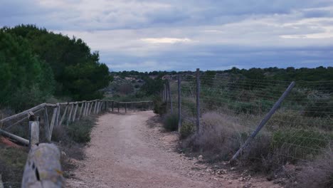 timelapse y zoom out mostrando nubes grises sobre un sendero solitario al lado de una cerca