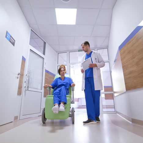 patient in a wheelchair talking to a doctor. nurse pushing a female patient in a wheelchair along the corridor in the modern clinic. hospital hallway.