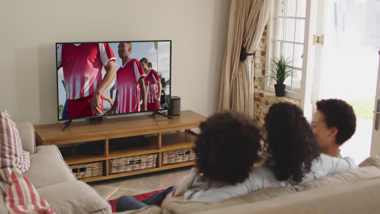 Famiglia felice seduta a casa insieme che guarda una partita di hockey in TV