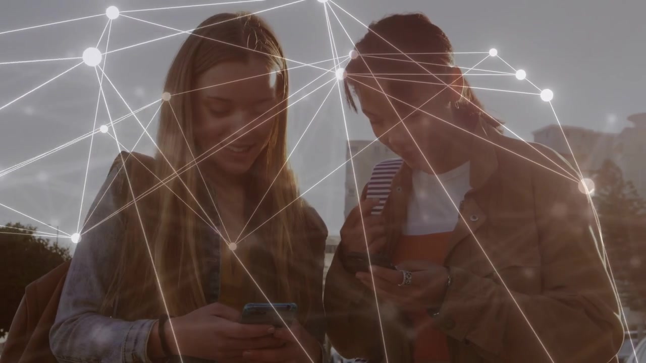 Two teens tapping phones and leaning in comparing content in urban tech network overlay glowing