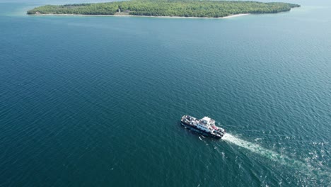 drone view looking down on a ferry traveling with cars and people to an island