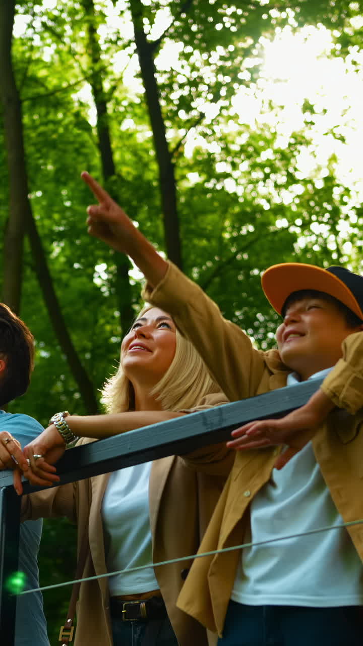 Glad familie som ser opp og smiler i en solrik park