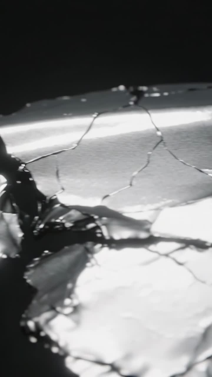 Vertical video: Camera panning right to reveal metallic foil sheet in black studio, exposing cracks