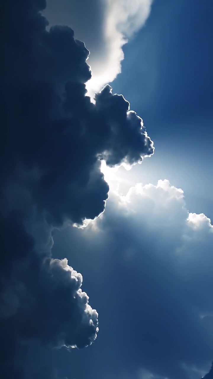Sunbeams Shining Through Dark Dramatic Clouds in Blue Sky