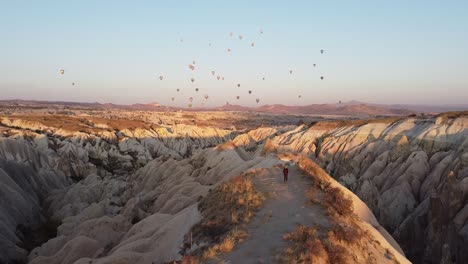 walking in cappadocia at sunrise with colorful balloons in the sky