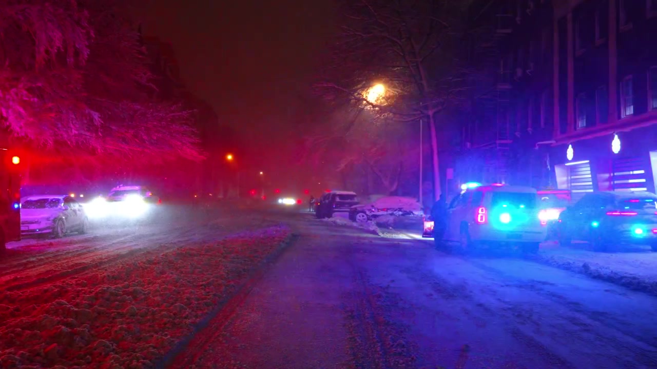 Ground level view of snowy road with blurred emergency lights. Low angle perspective of a snow-covered urban road at night with vibrant red and blue light reflections.