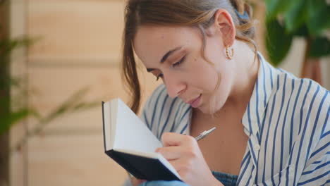 Woman-Writing-Notes-Close-Up-on-Sofa