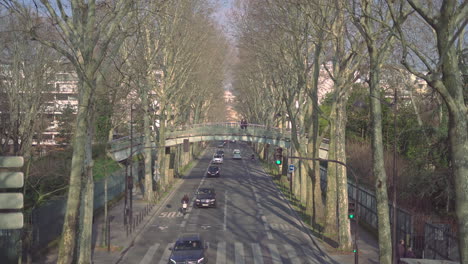 view of a pedestrian bridge with people on it over a two lane road in paris, france