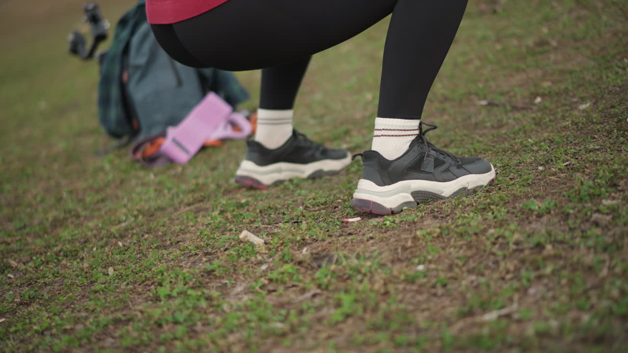 Outdoor Activity With Sneakers, Closeup Of Woman Adjusting Sneakers Outdoors On Grass With Accessories Nearby, Woman Outdoors On Grass Adjusting Her Sneakers While Nearby Accessories Are In View