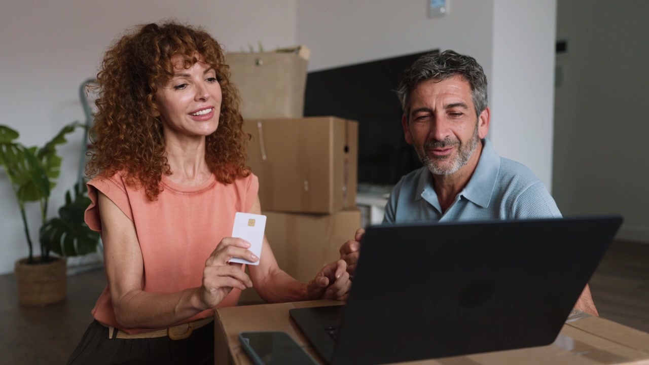 Couple Using Credit Card for Online Shopping in New Home