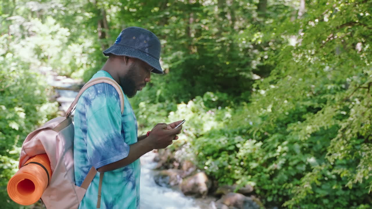hombre caminando en el bosque, usando el teléfono