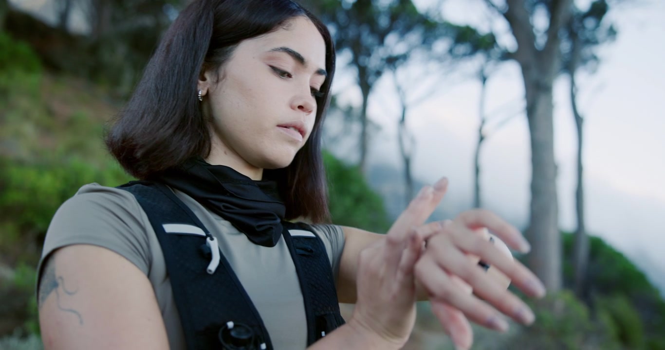 Giovane runner su sentiero che controlla lo smartwatch durante l'allenamento all'aperto