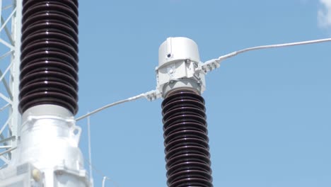 muchos aislantes eléctricos de alto voltaje en la subestación de energía contra un fondo de cielo azul