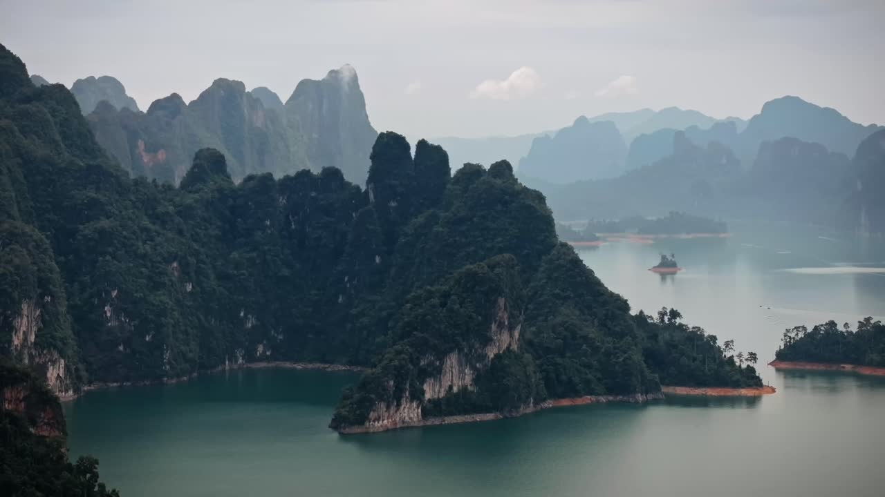 Drone footage of Khao Sok National Park shows limestone mountains, dense jungle, and tranquil lake views in Southern Thailand's wild rainforest landscape