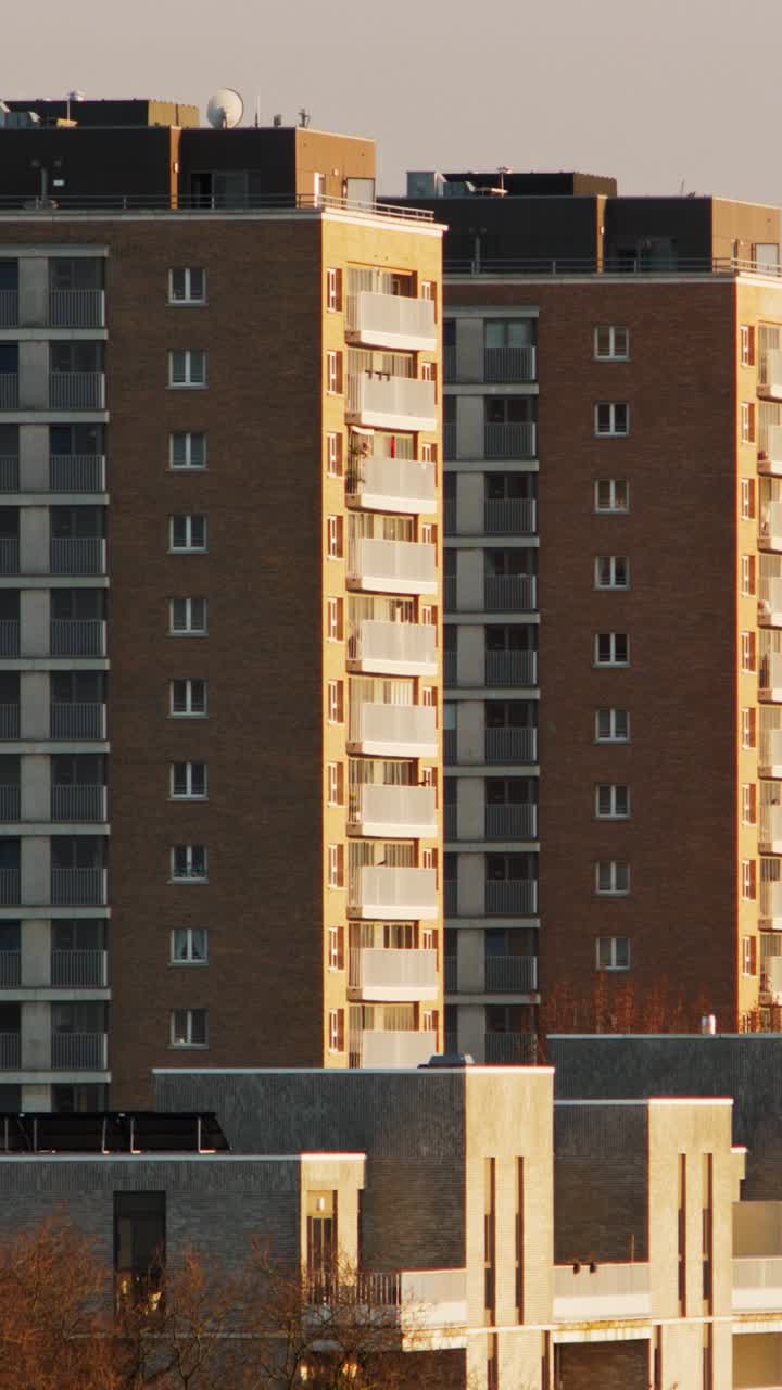 Smooth pan reveals two matching brick high-rise apartment blocks glowing in warm evening light