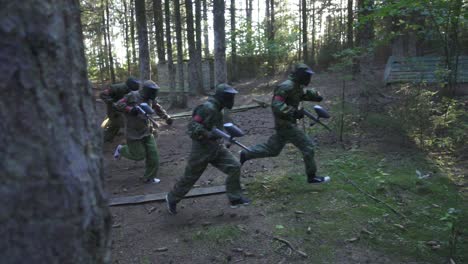 paintball player running on battle field during shooting game in summer forest