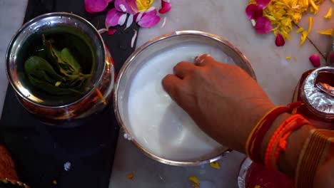 women washing silver coin with milk, honey, and curd before offering to goddess lakshmi during diwali pooja celebration in india