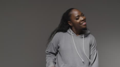 Studio-Portrait-Shot-Of-Young-Woman-Wearing-Hoodie-Dancing-With-Low-Key-Lighting-Against-Grey-Background-7