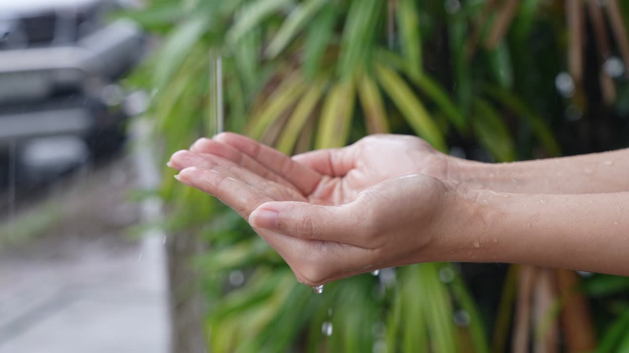 Closeup on hands movement, young white skin hands collecting a water or raindrops, seasoning concept, touching a power of nature, refreshing activity, clear water splashing out of human palms slowly