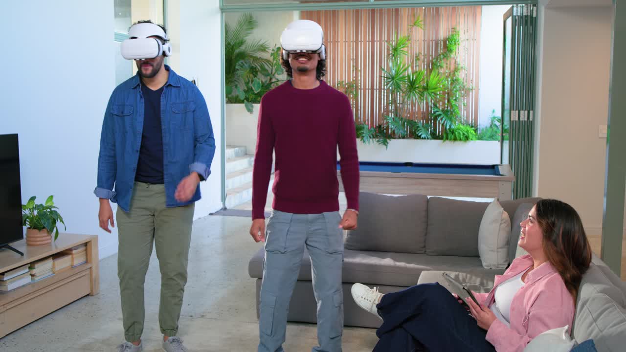 Amici che indossano visori VR, si allungano, schivano e reagiscono mentre giocano in un soggiorno moderno