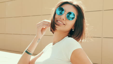 mujer con gafas de sol redondas sonriendo al aire libre