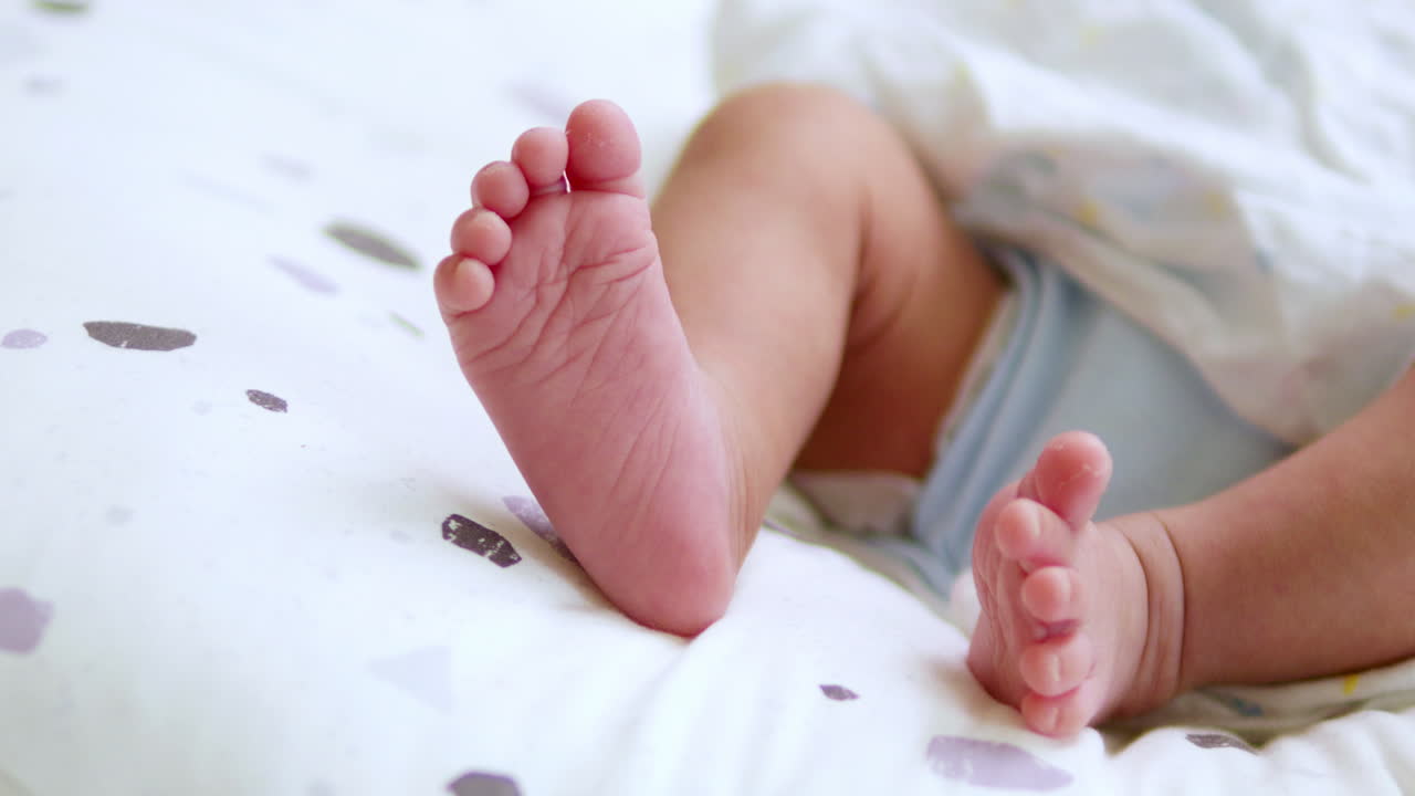 A baby's tiny feet are kicking and stretching as it is lying on its crib inside the nursery