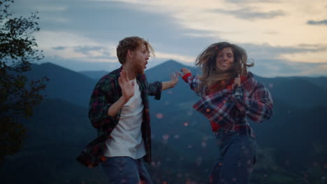 amigos alegres bailando en las montañas del crepúsculo. familia alegre disfrutando de un divertido viaje