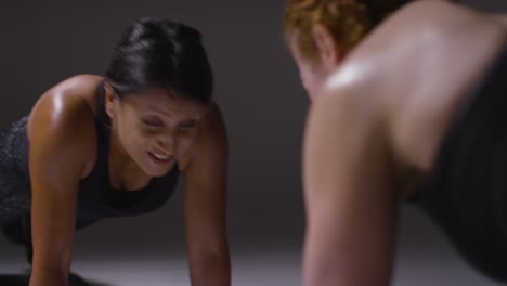 Close-Up-Studio-Shot-Of-Two-Mature-Women-Wearing-Gym-Fitness-Clothing-Doing-Plank-Exercise-Together-1