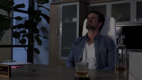 frustrated boss working after hours takes a drink of whiskey