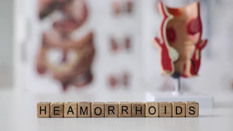 wooden blocks spelling hemorrhoids with anatomical models in background