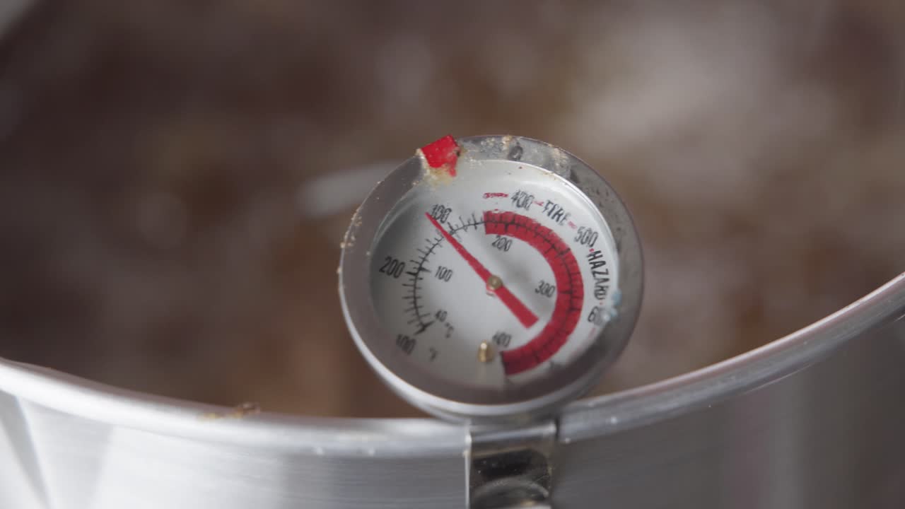 A detailed close-up shot of a turkey frying in hot, bubbling oil inside a deep fryer. Boiling grease rapidly surrounds the poultry as it cooks, creating intense texture, movement, and sizzling action