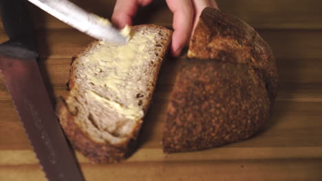 static close up shot of a delicious and tasty slice of sourdough bread just after being cut, buttered then taken a bite out of and placed back on the board